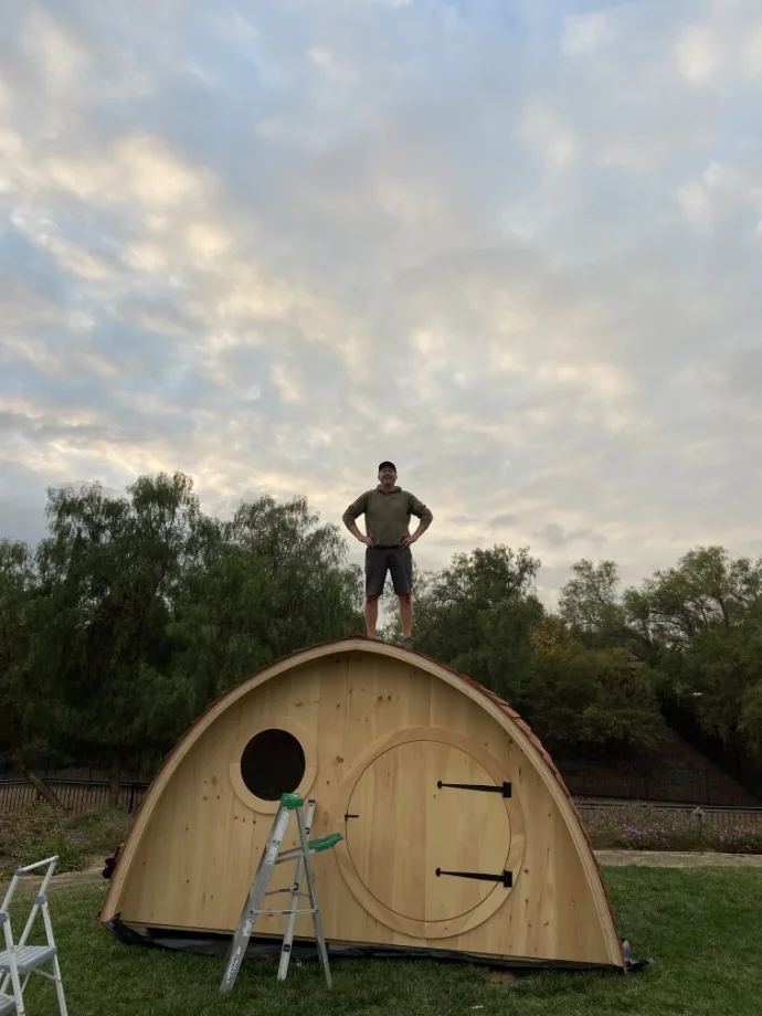 Zeb standing on the hobbit house he built.